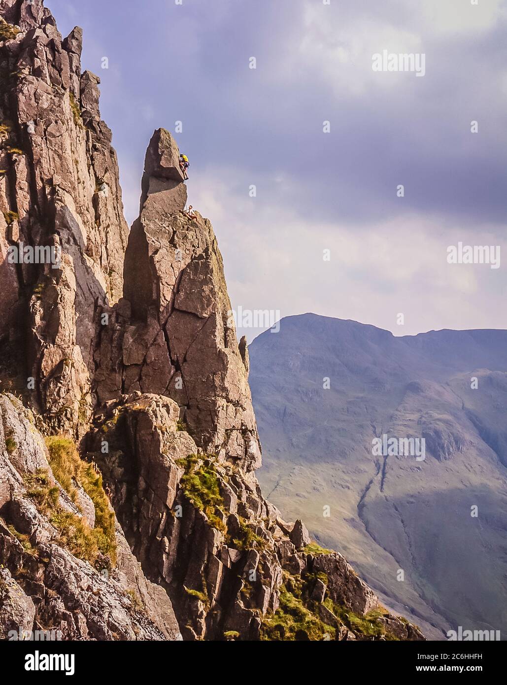 L'immagine mostra gli scalatori in azione scalando la formazione rocciosa di Napes Needle sul lato della montagna di Great Gable alla testa della valle di Wasdale nel Distretto Inglese del Lago essendo un obiettivo popolare come diritto di passaggio con gli scalatori di roccia di ogni generazione Foto Stock