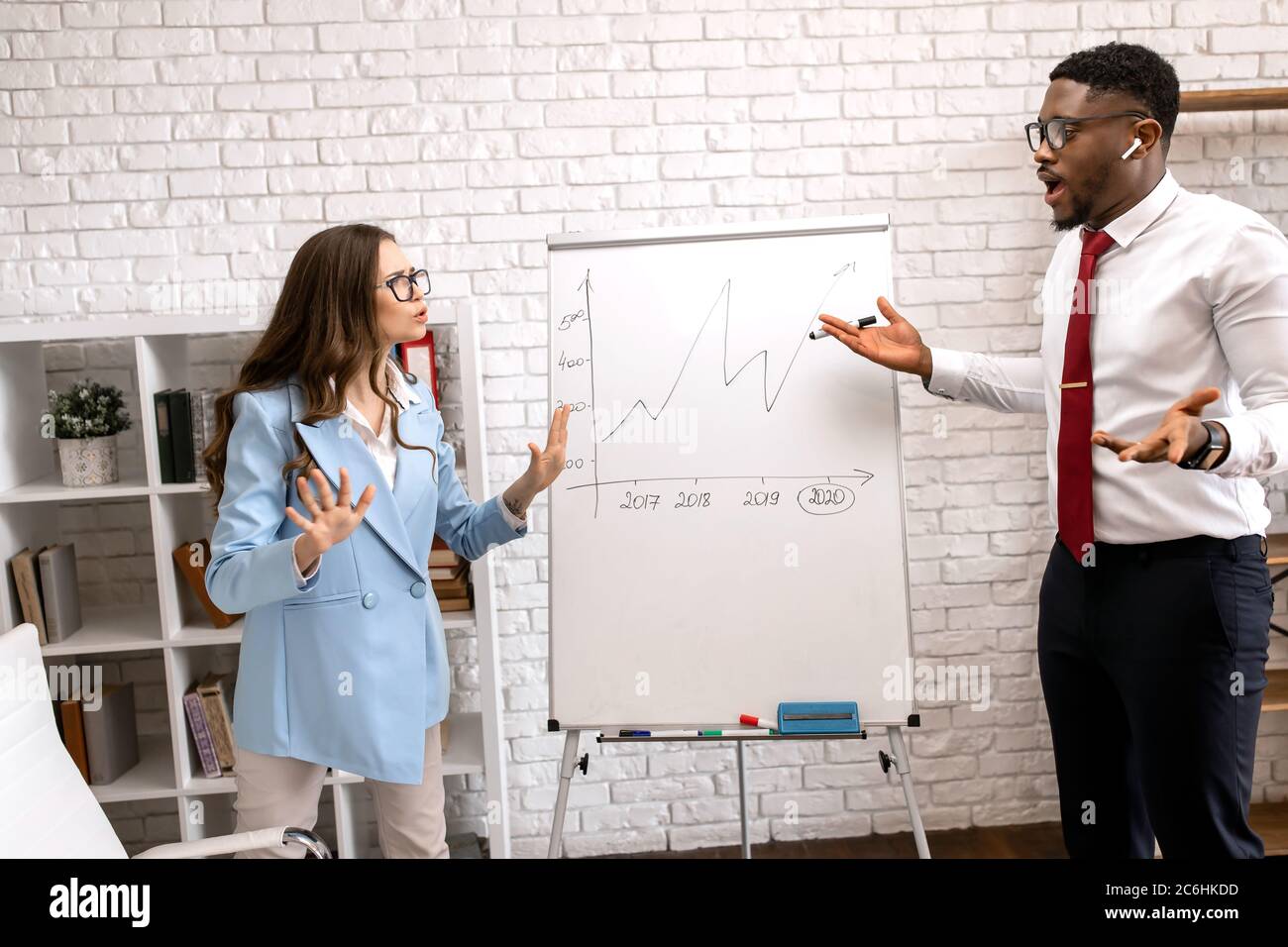 La controversia sul lavoro. Uomo d'affari africano che mostra un grafico al suo collega infastidito in un ufficio moderno Foto Stock