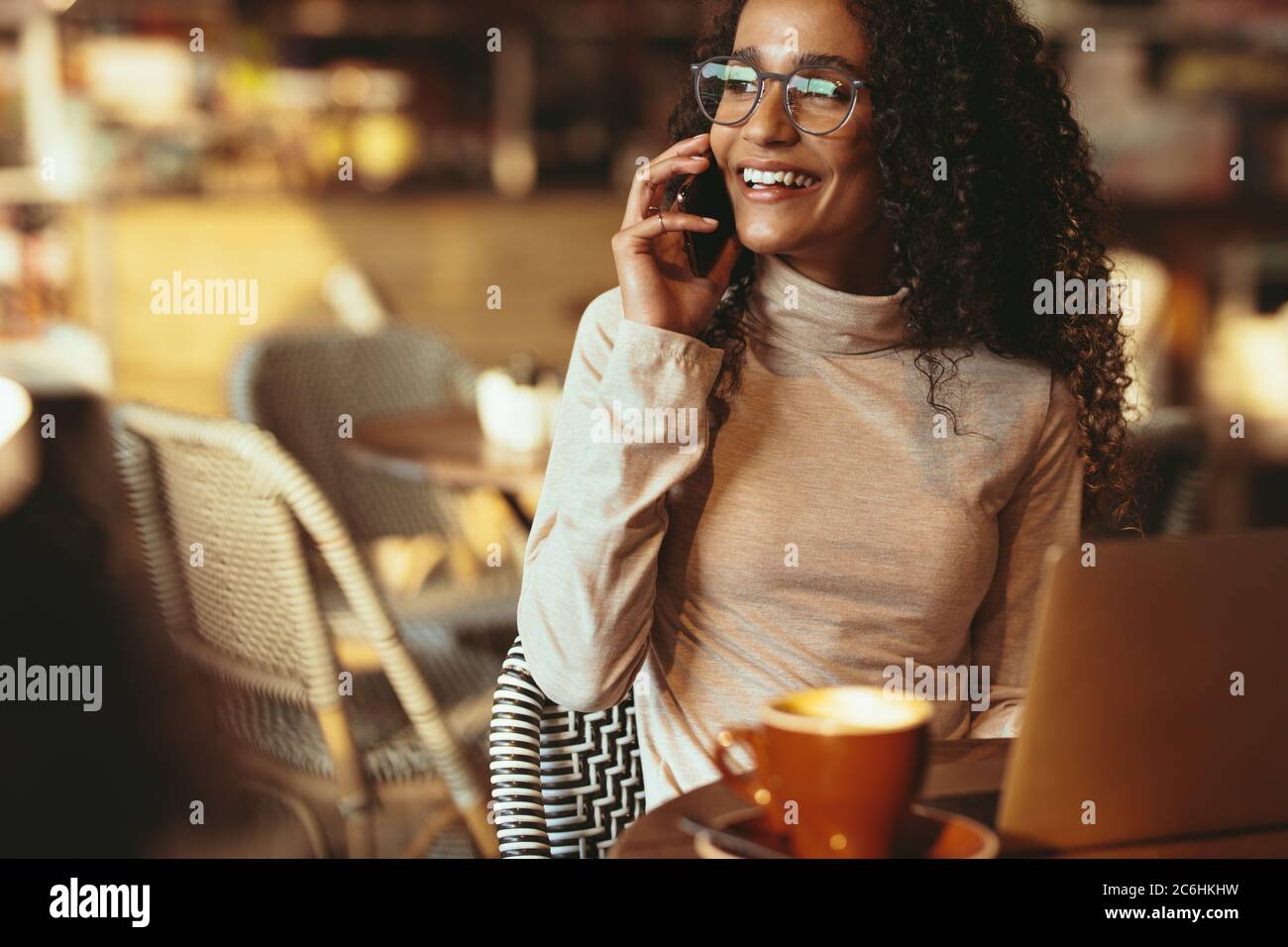 Bella donna che parla al telefono e che guarda via. Donna seduta al caffè che effettua la chiamata. Foto Stock