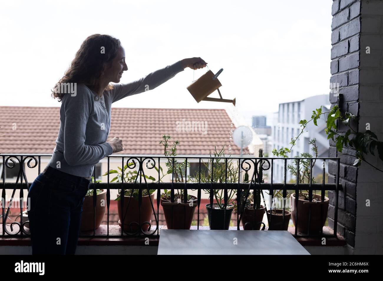 Donna annaffiatura piante nel balcone Foto Stock