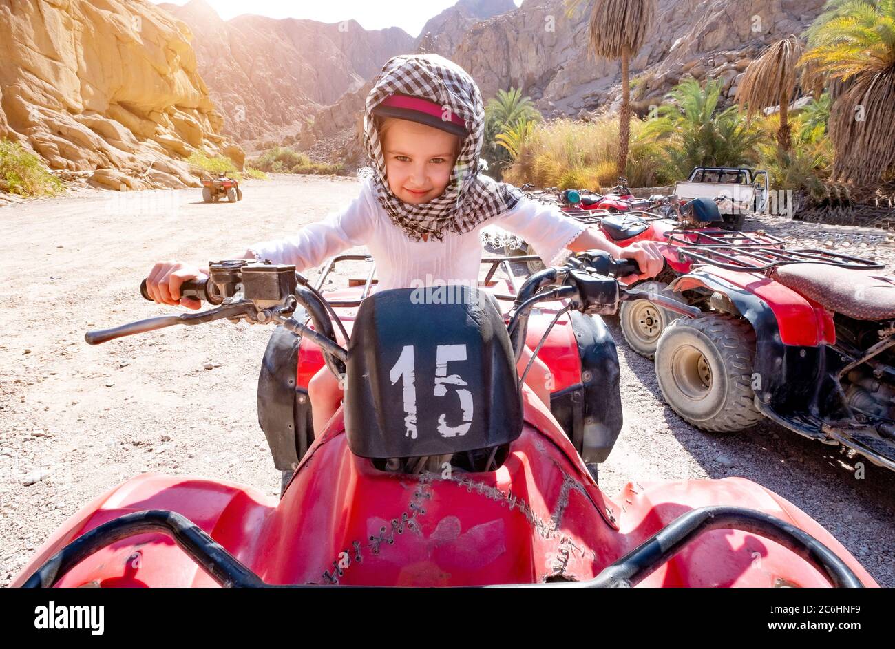 Bambina in keffiyeh su una quad rossa nel deserto Foto Stock