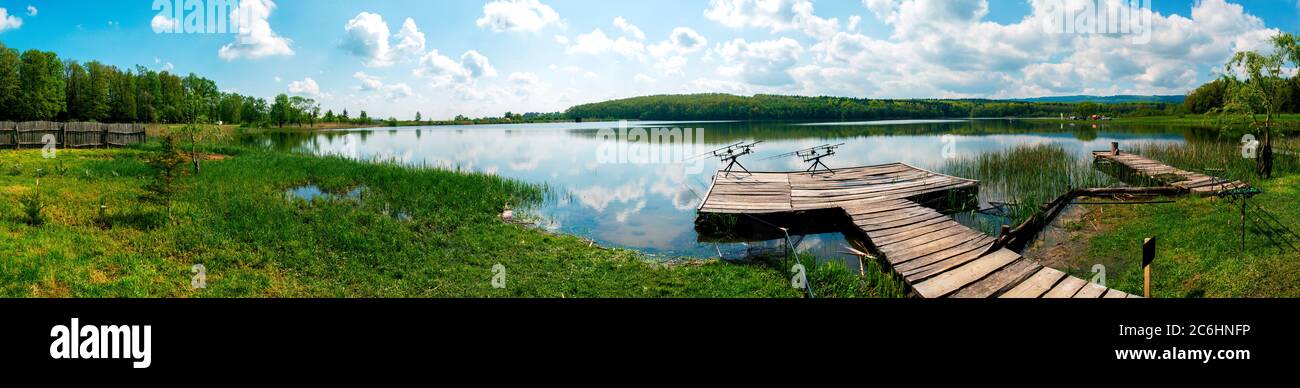 palo da pesca con bellissimo lago, montagne, foresta e cielo di acciaio sfondo. Strumento di pesca e concetto sportivo Foto Stock
