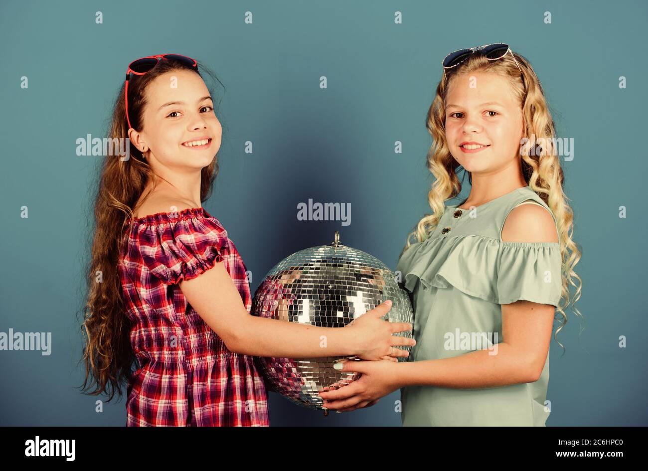 Sorelle amici con palla da discoteca. Iniziare a parte. Allegro kids tenere palla da discoteca. Discoteca danze. Musica retrò. Gli specchi riflettenti discoteca luci di atmosfera. Holiday celebrazione. Concetto di intrattenimento. Foto Stock