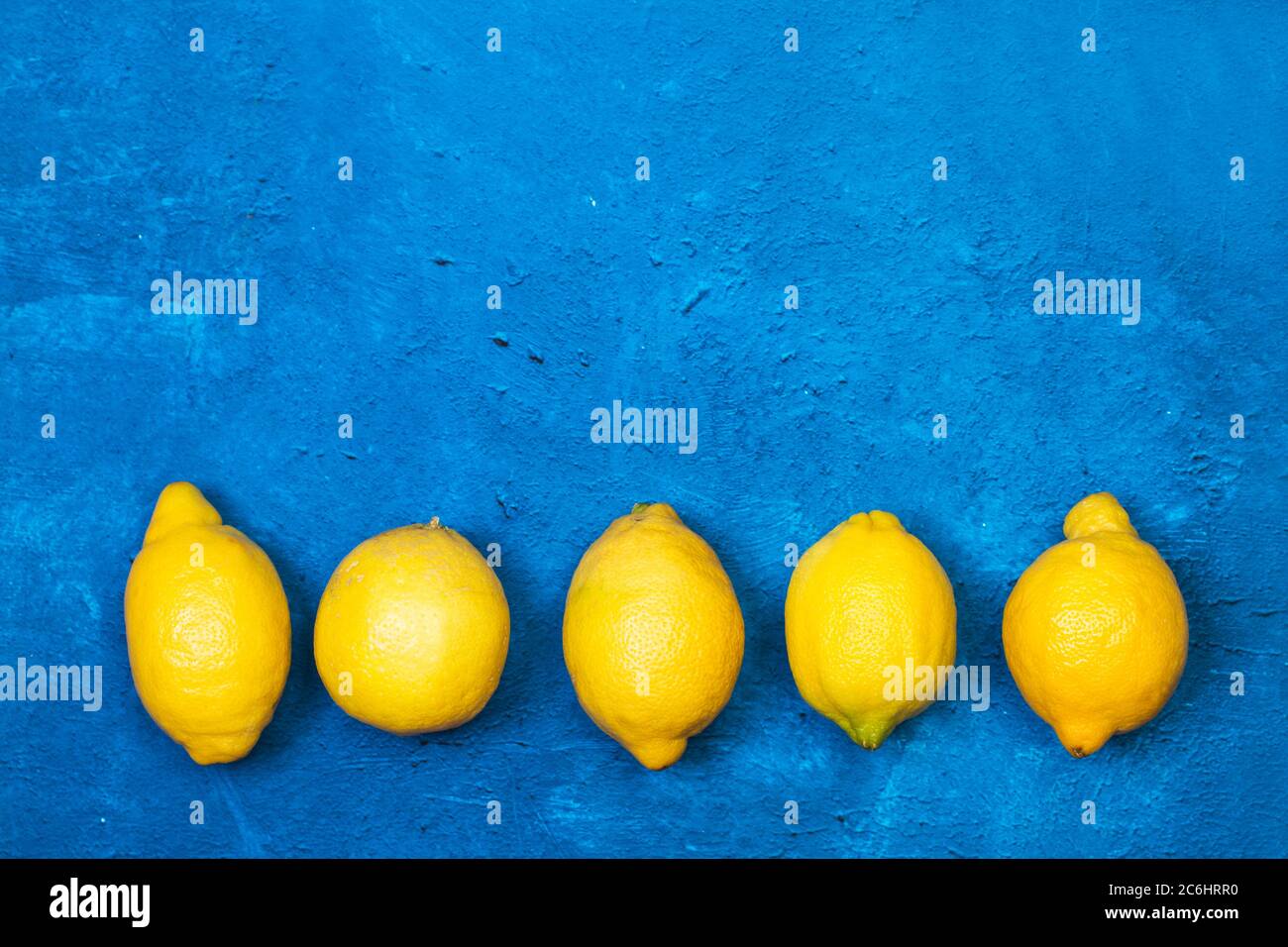 Cinque limoni su un classico sfondo blu testurizzato in una vista dall'alto Foto Stock