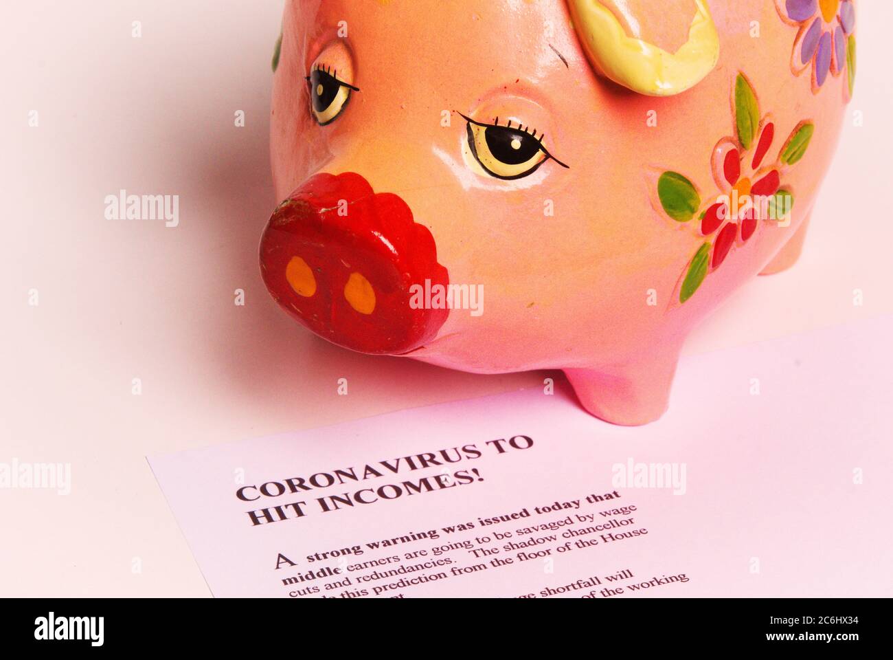 Immagine di concetto finanziario. Costo di Covid 19 per economia e risparmio. Sad piggy bank e articolo immaginario su Coronavirus. Idea carenza di contanti, c Foto Stock