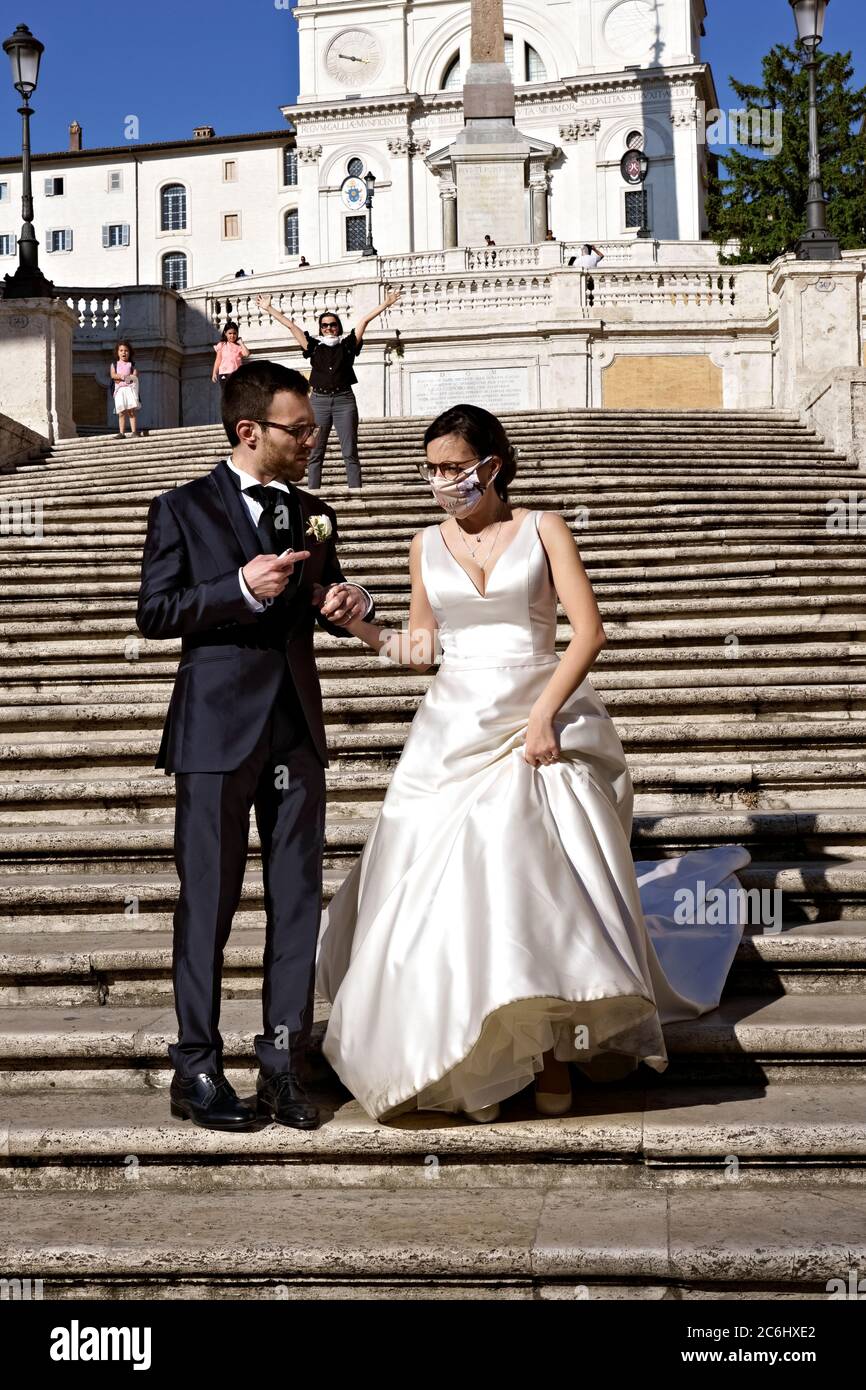 Coppia sposata di recente con maschera medica Coronavirus, che posa per scattare foto sulla scalinata di Spagna. Matrimonio al tempo di Covid 19 Roma Italia Europa Foto Stock