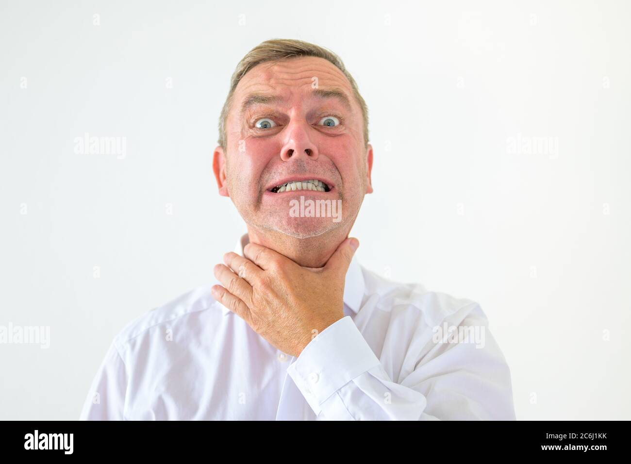 L'uomo esasperato alla fine del suo laccio afferrando la gola con la mano con grandi occhi fissi e denti che si annidano in un portr di testa e spalle Foto Stock