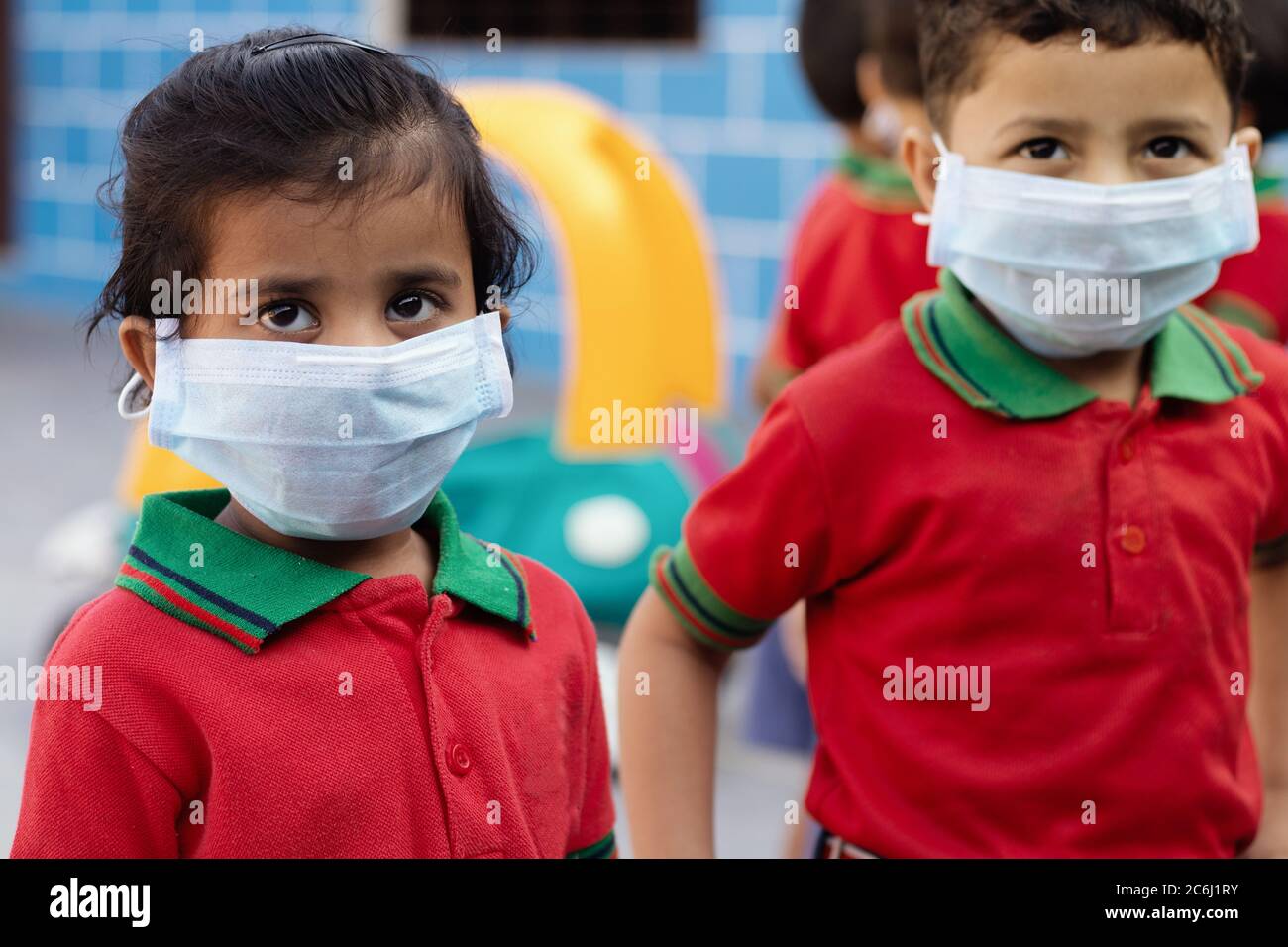 Bambini piccoli a scuola con maschera medica guardando la fotocamera - concetto Scuola riaprire o tornare a scuola dopo covid-19 o coronavirus Pandemic. Foto Stock