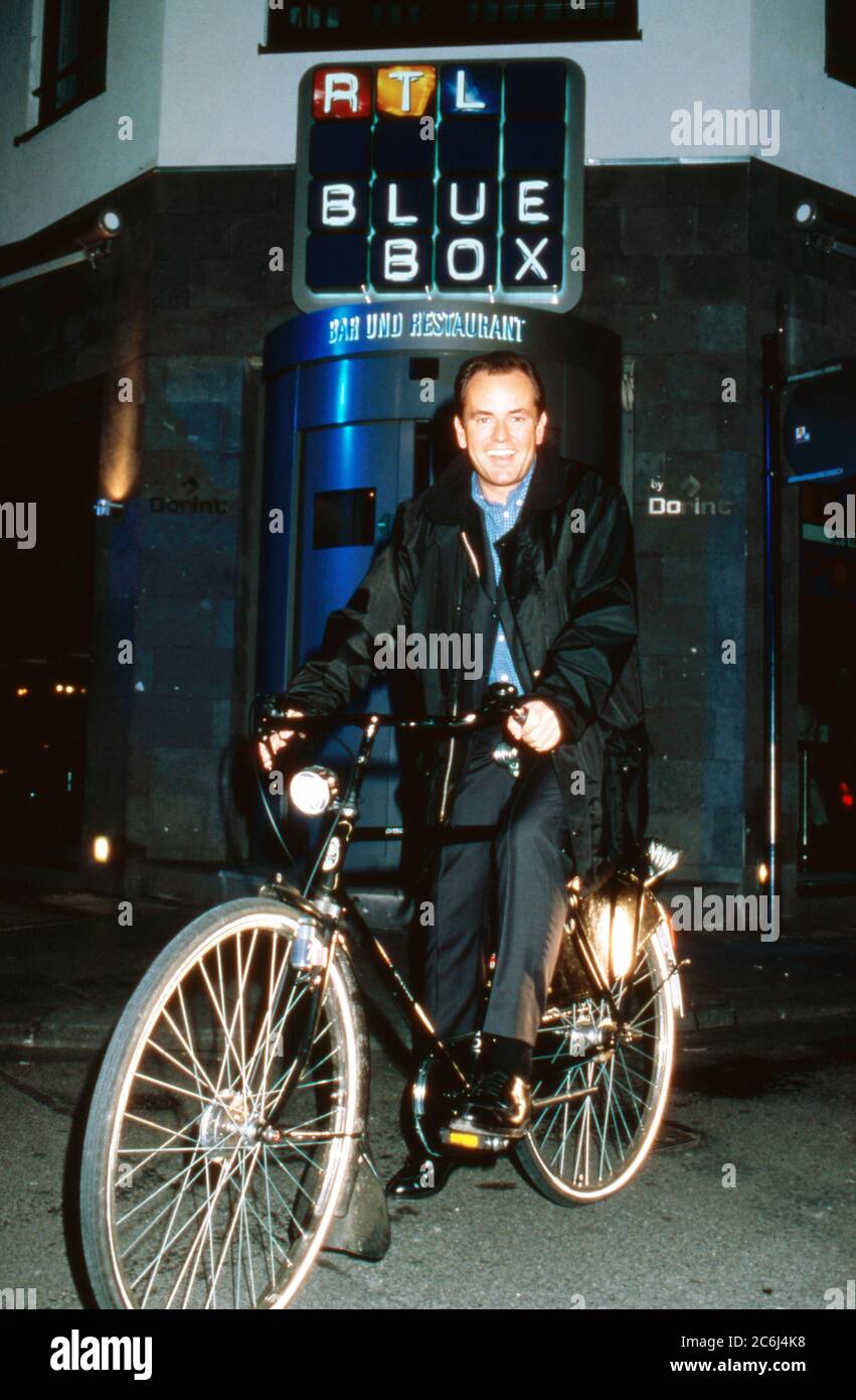 Wolfram Kons, Nachrichtensprecher bei RTL, mit dem Fahrrad vor dem Bar Restaurant 'RTL Blue Box' in Köln, Deutschland um 1999. Foto Stock
