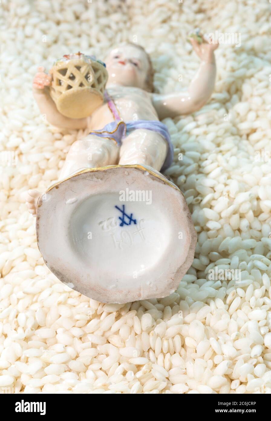 Simbolo delle spade blu incrociato su un antico ragazzo di porcellana Meissen Cherub con cesto di fiori Foto Stock