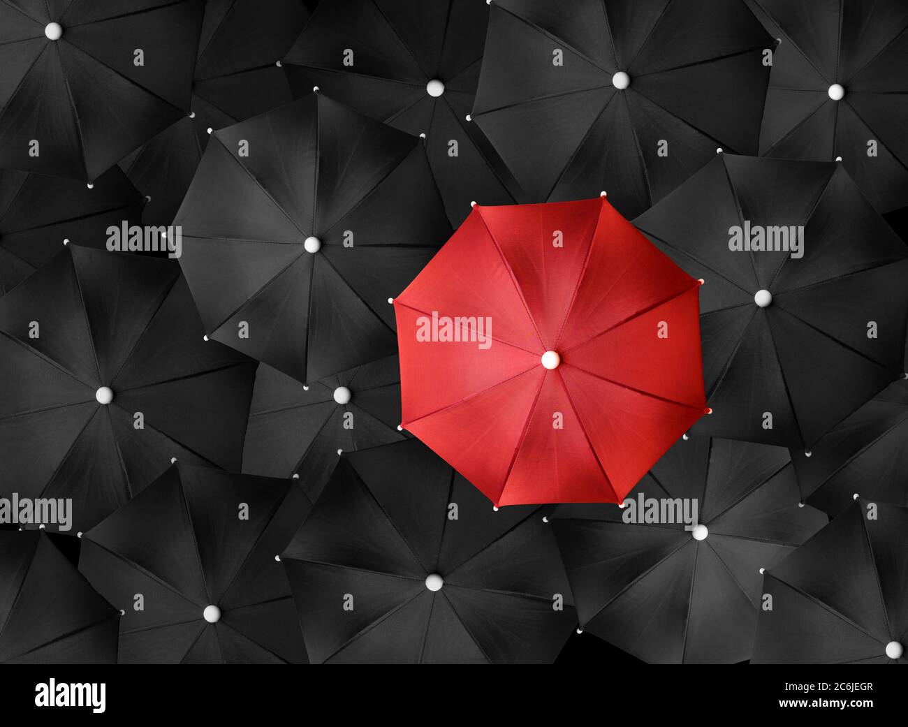Immagine concettuale con un sacco di ombrelli neri e un ombrello rosso che si distingue, essere unico Foto Stock