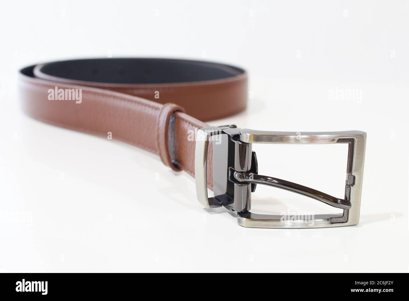 Cintura in pelle marrone isolata su bianco. Cinghia maschio arrotolata Foto Stock