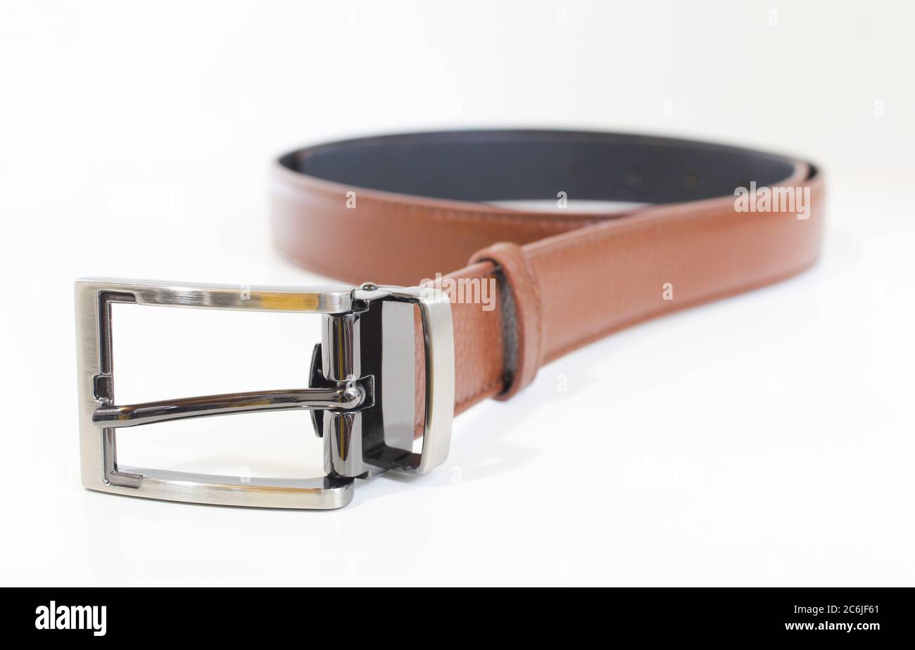 Cintura in pelle marrone isolata su bianco. Cinghia maschio arrotolata Foto Stock