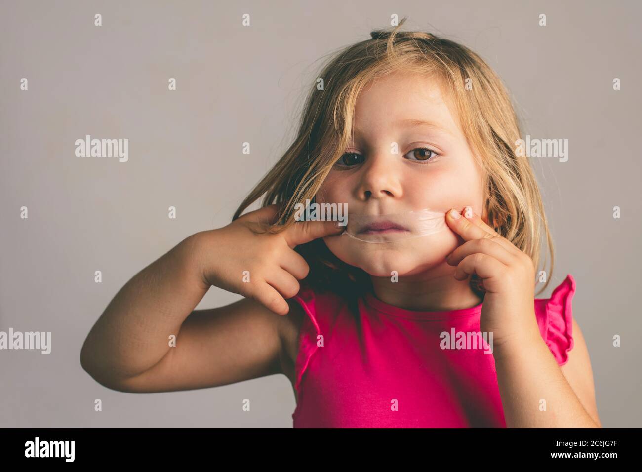 4 anni ragazza con un nastro che chiude la bocca. studio ritratto Foto Stock