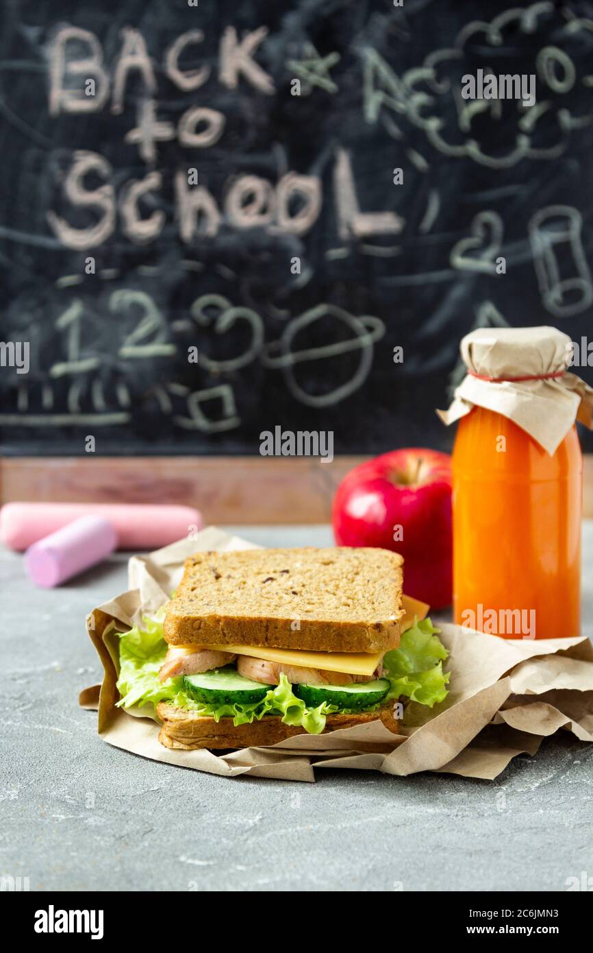 Pranzo sano scuola: Sandwich con insalata, formaggio e cetriolo, succo di frutta e mela. Nutrizione sana per i bambini. Pausa scolastica. Foto Stock