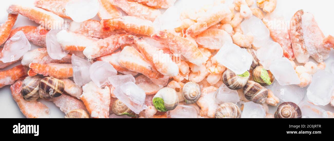Assortimento di pesce surgelato su cubetti di ghiaccio, gamberi, lumache di molluschi Babylonia areolata, langoustine, ricche di iodio, antiossidanti e vitamina, vicino Foto Stock
