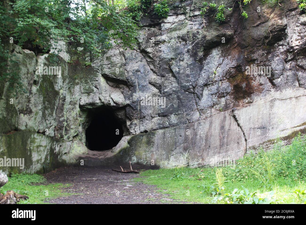 Una parete rocciosa frastagliata con un tunnel/foro nella grotta sul bordo di Alderley a Cheshire, Inghilterra Foto Stock