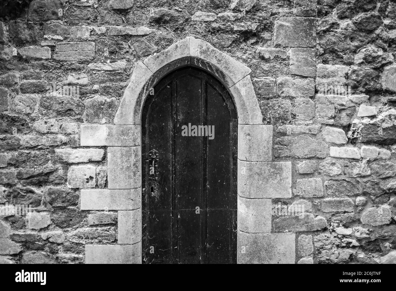 Vista monocromatica di una famosa porta medievale della chiesa visto chiuso a chiave. La pietra ristrutturata è visibile. Foto Stock