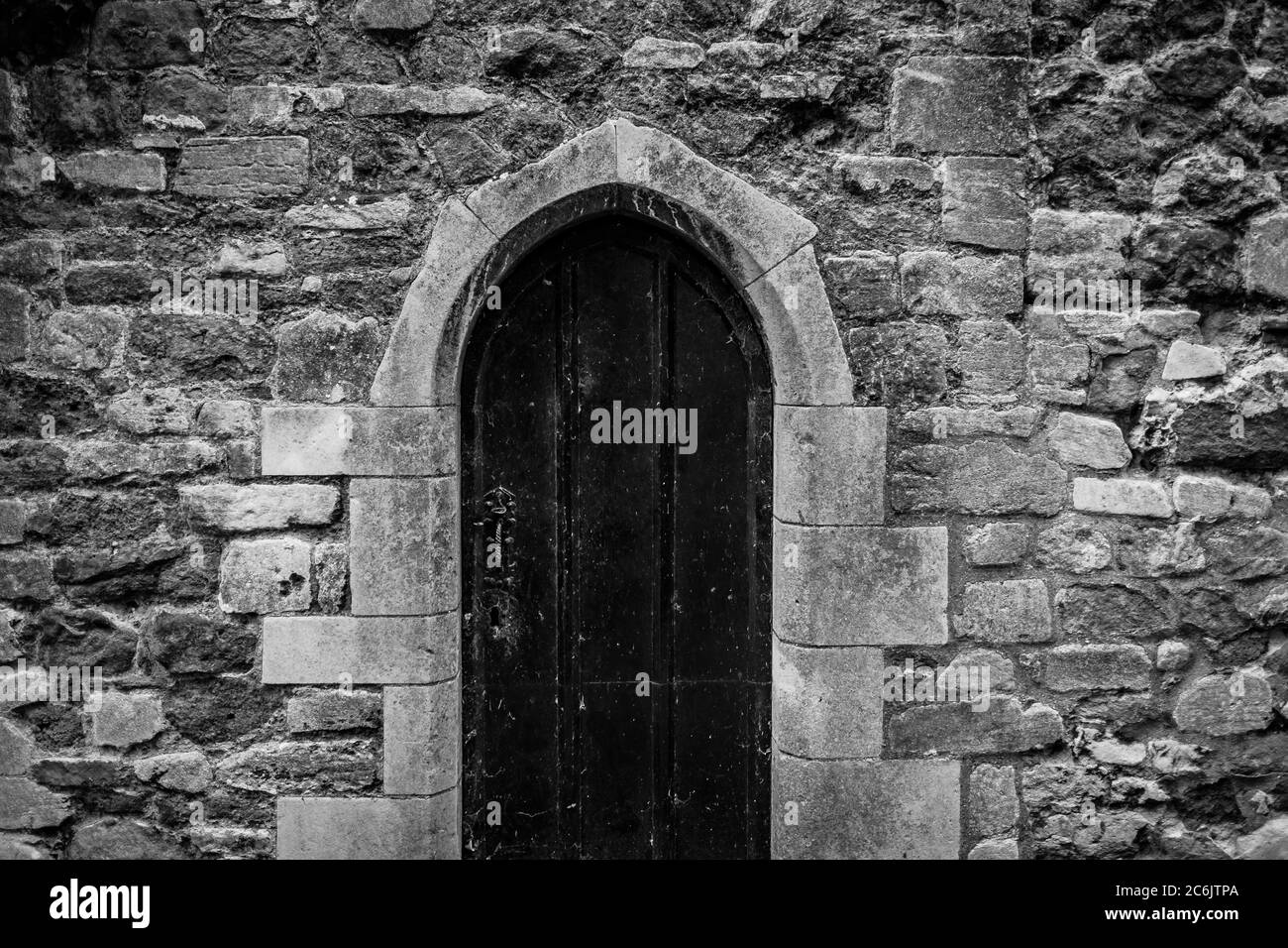 Vista monocromatica di una famosa porta medievale della chiesa visto chiuso a chiave. La pietra ristrutturata è visibile. Foto Stock