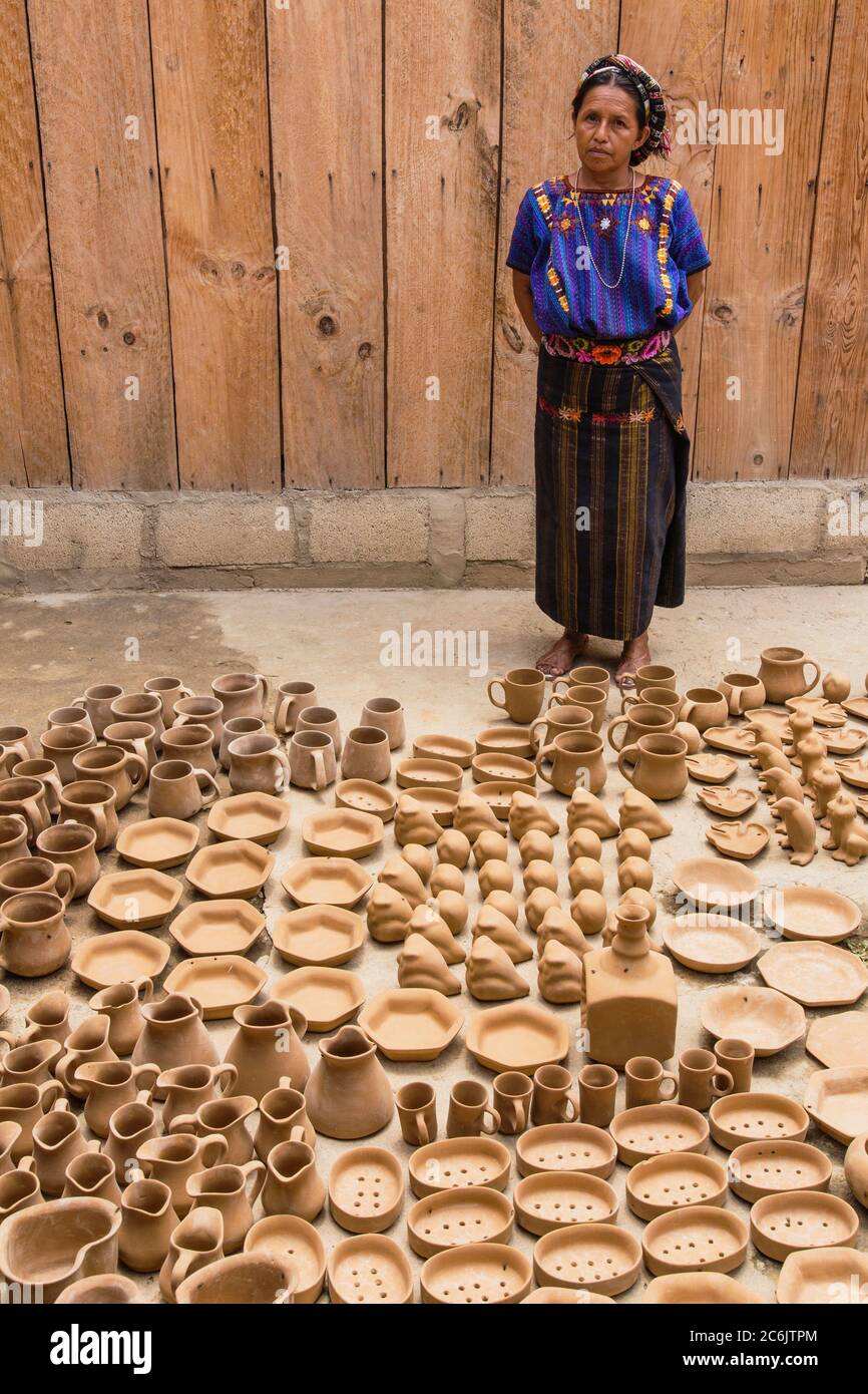 Guatemala, Solola, San Antonio Palopo, una donna maya Cakchiquel alla sua officina di ceramica nel vestito tradizionale compreso l'elaborato cinta o avvolgi capelli, blusa di huipil blu intrecciato, faja o cintura, e gonna di corte. Foto Stock