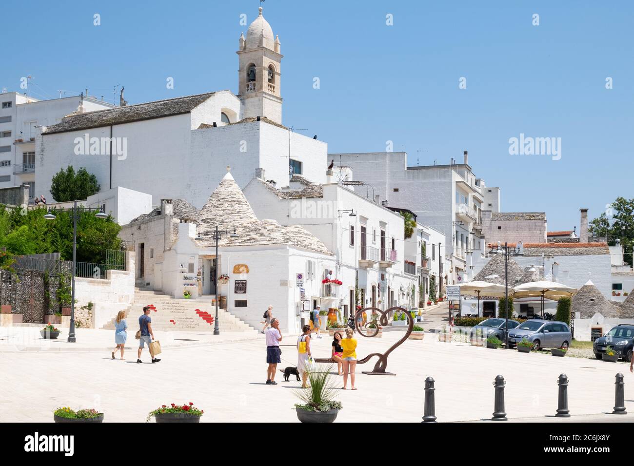 Puglia, Italia - Alberobello, turisti camminano per le strade della città pugliese con tetti a forma di cono costruiti in pietra, città dell'UNESCO. Foto Stock