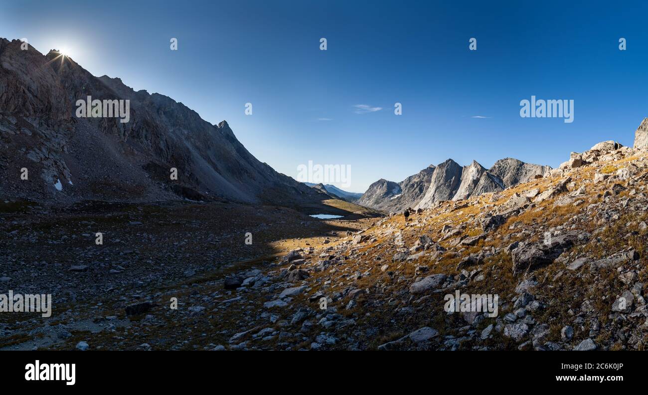 Un backpacker sale RAID/Bonneville Pass mentre il sole sorge sulle vette ad est. Wind River High Route nel Wind River Range del Wyoming. Foto Stock