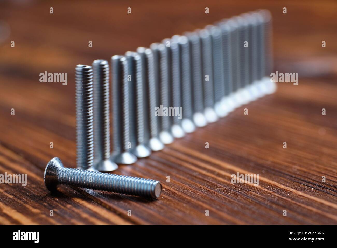 Bruciare e perdere forza sul lavoro. Viti metalliche su fondo in legno Foto Stock