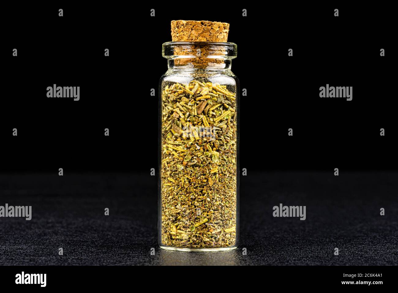Macro shot di erbes de hrovence in una piccola bottiglia di vetro chiusa con un sughero, isolato su sfondo nero. Foto Stock