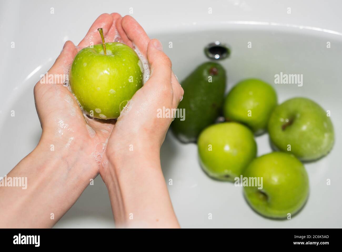 Lavare la frutta. Mani e mela verde saponata Foto Stock