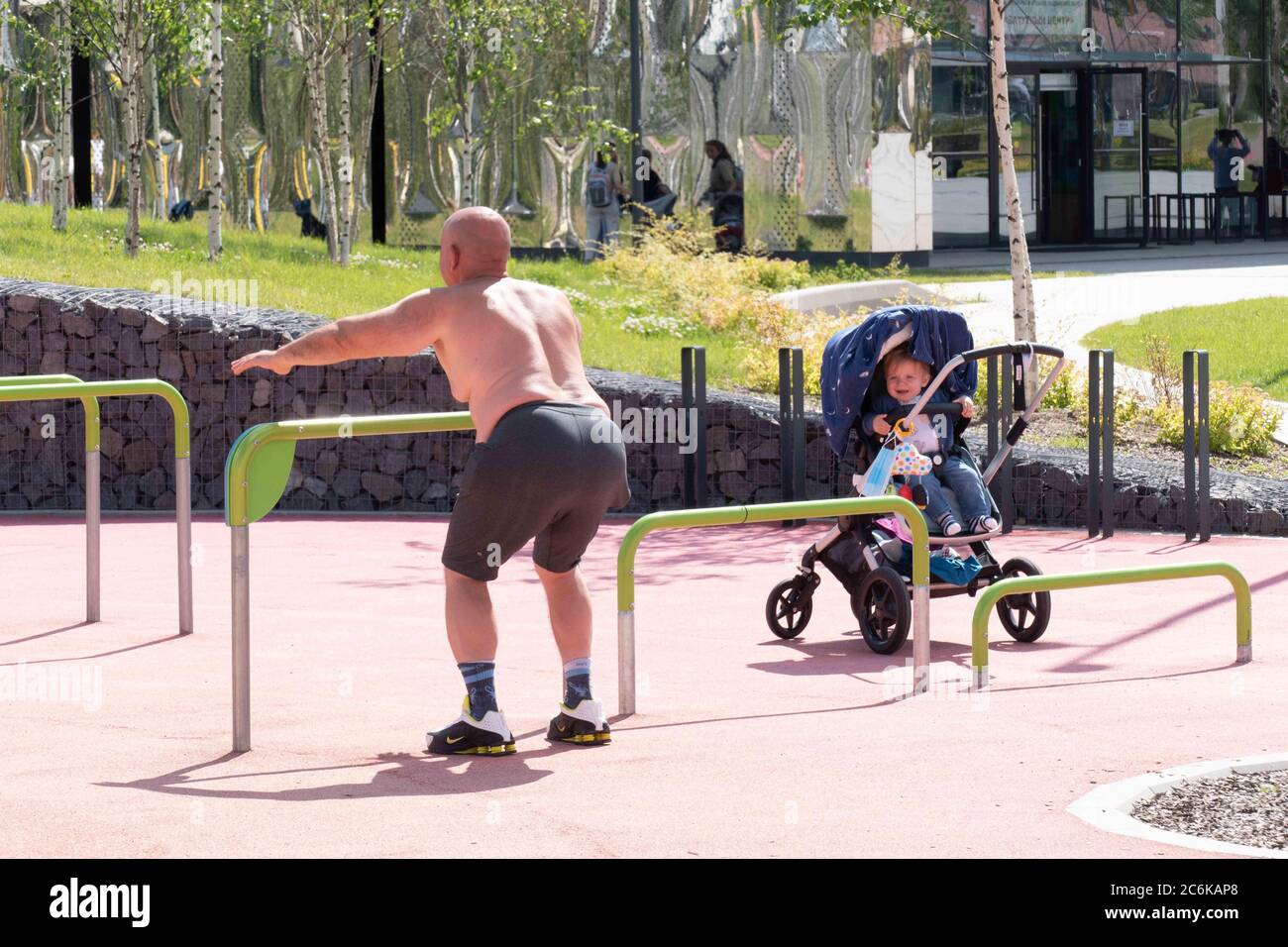 HLS - un uomo anziano in pantaloncini e un il bambino in passeggino piange Foto Stock