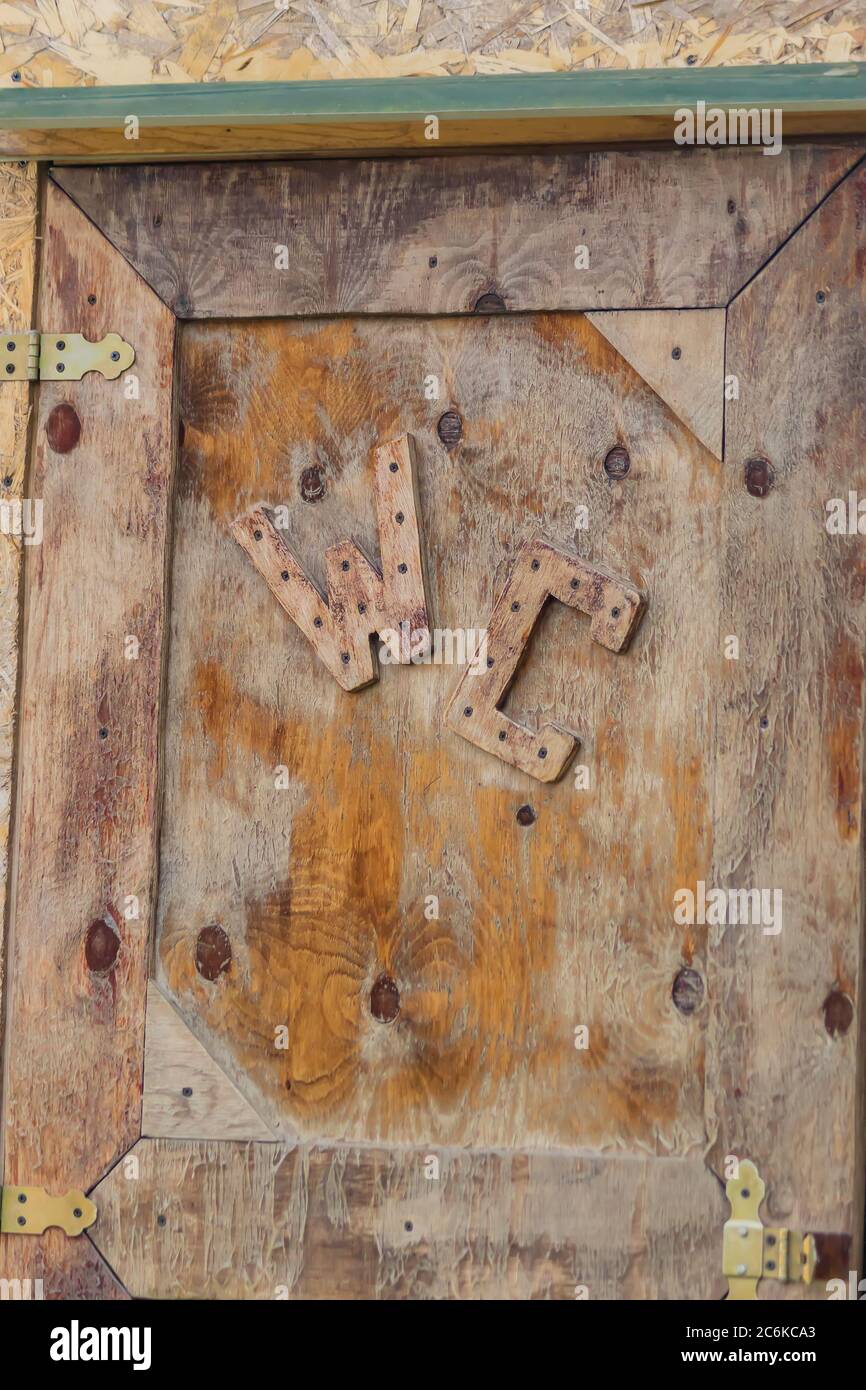 Insegna WC sulla vecchia porta di legno. Foto Stock