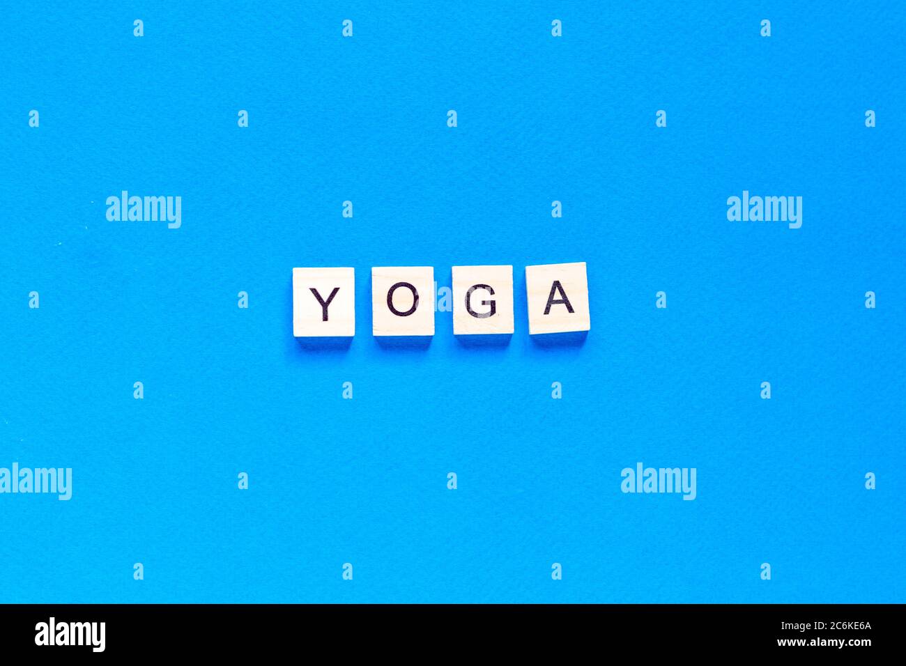 La parola YOGA scritta in legno tipo letterpress su sfondo blu. Vista dall'alto. Layout piatto. Foto Stock