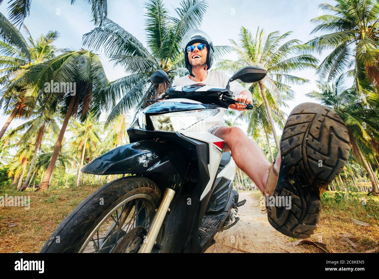 Uomo in casco sicuro che cavalcano moto in giungla. Immagine esotica concetto di vacanza. Foto Stock