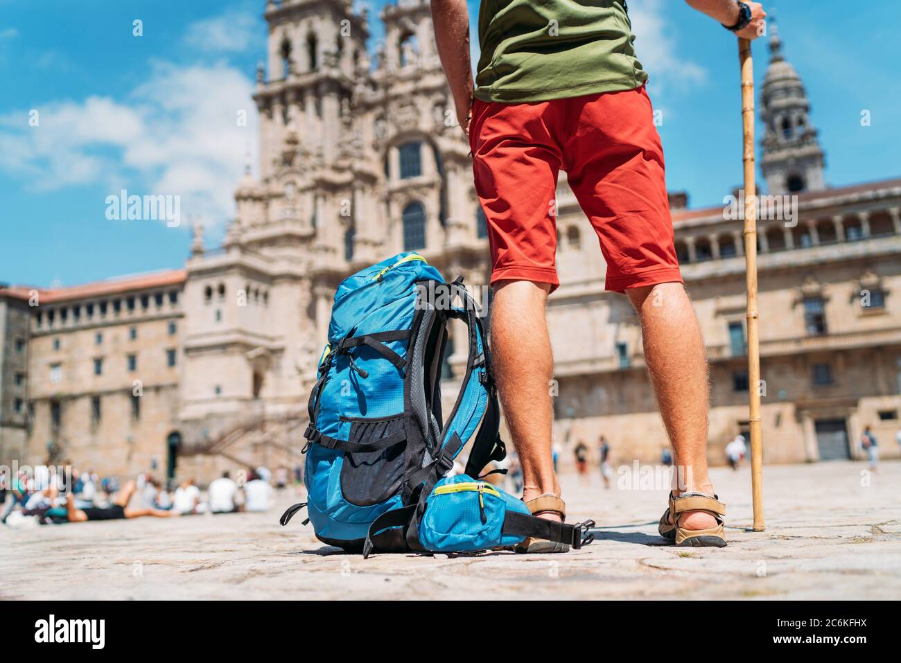 Gambe stanche primo piano foto di giovane zaino in spalla uomo pellegrino in piedi sulla piazza Obradeiro (plaza) - la piazza principale di Santiago de Compostela come un en Foto Stock