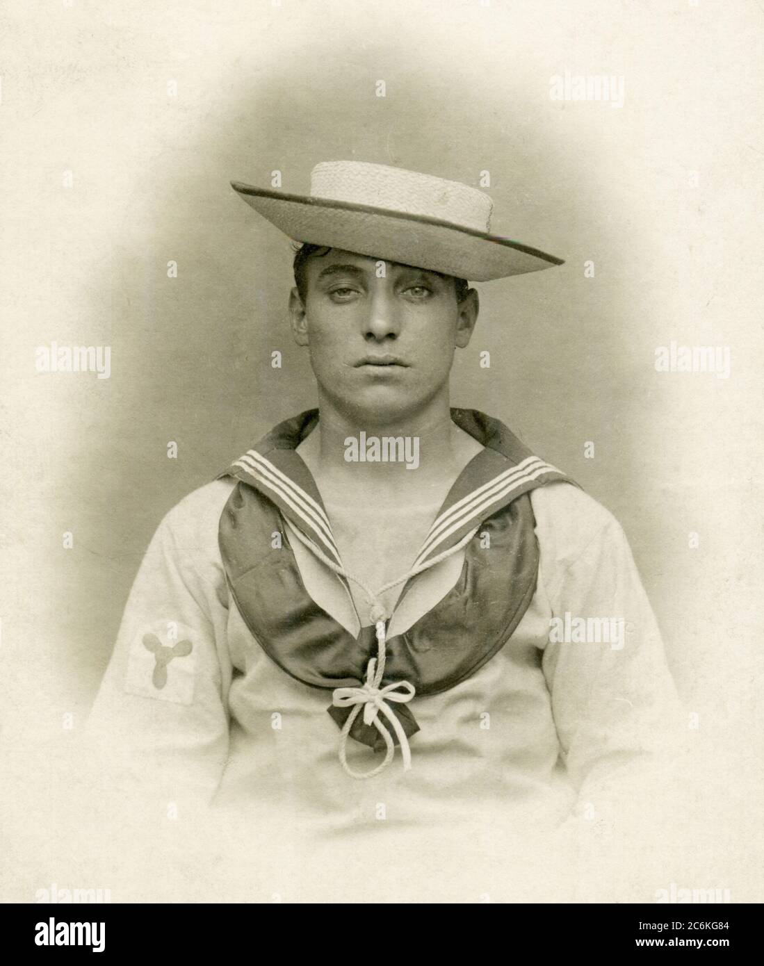 Un marinaio vittoriano Royal Navy con un vestito da marinaio tropicale bianco e un cappello di paglia sennet. Ha un insegne di rating stoker sulla sua manica. Circa 1900 Foto Stock