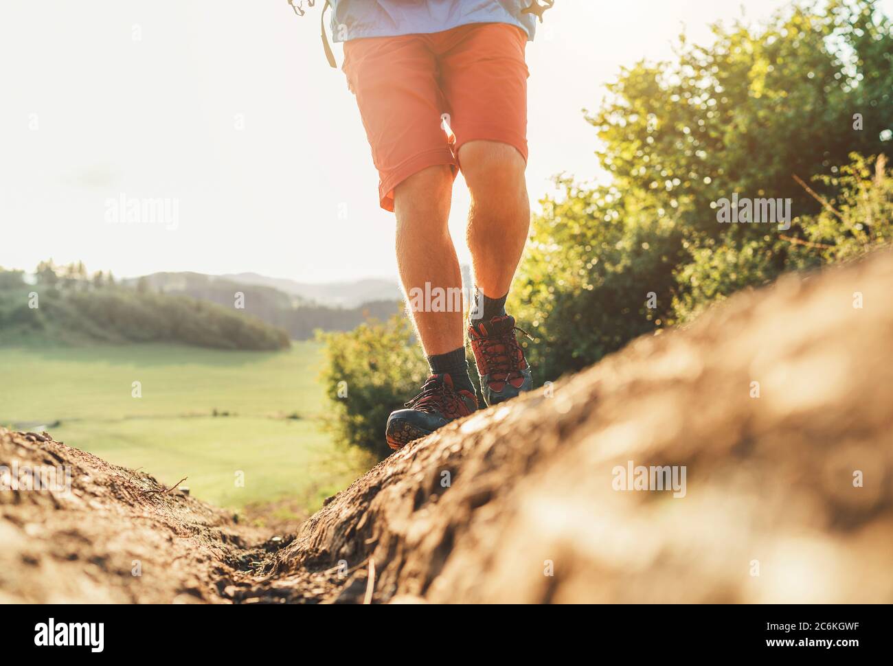 Primo piano immagine zaino in spalla piedi in scarpe da trekking su percorso di montagna sporco in estate giorno di sole. Foto Stock