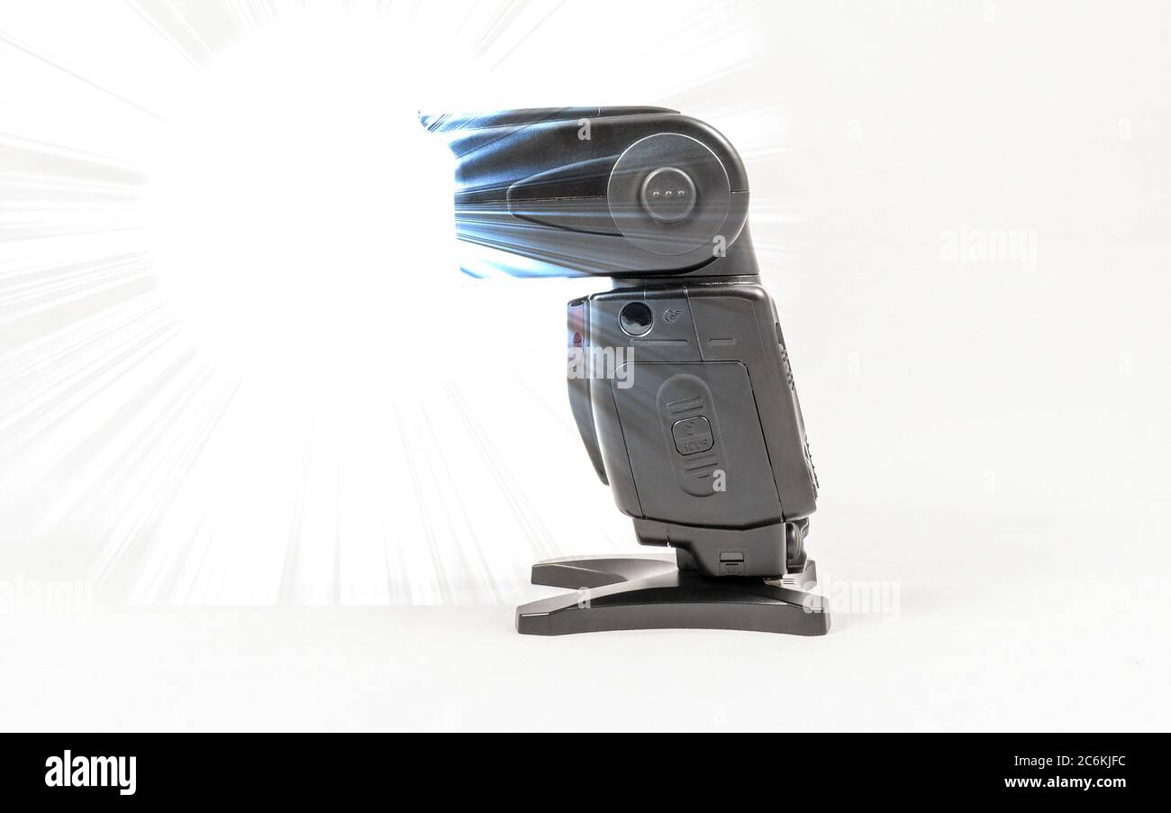 Vista laterale di un'unità flash esterna nera senza marchio per fotocamere DSLR con diffusore applicato durante le riprese Foto Stock