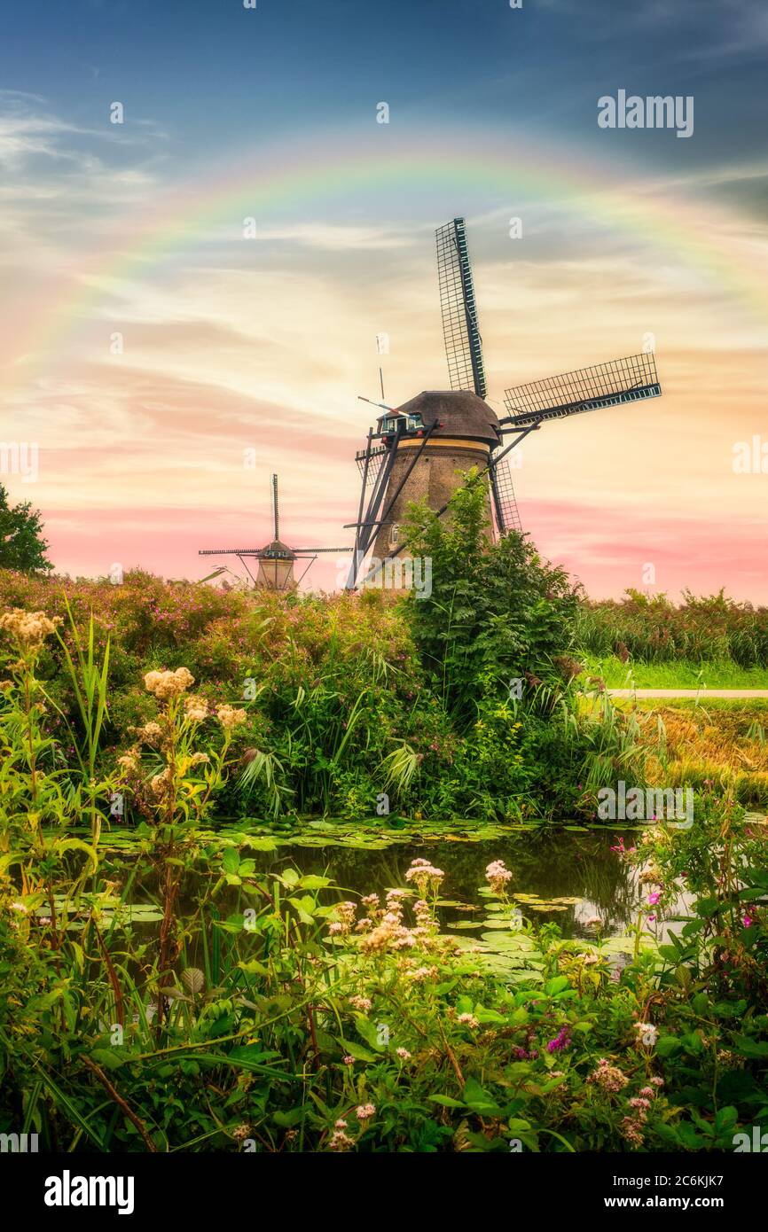 Splendidi mulini a vento olandesi e paesaggio sotto il cielo e l'arcobaleno del tramonto Foto Stock