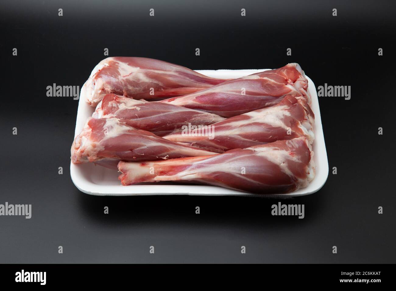 Grezzi agnello in un contenitore bianco di polistirolo isolato su sfondo nero con spazio per la copia del testo Foto Stock
