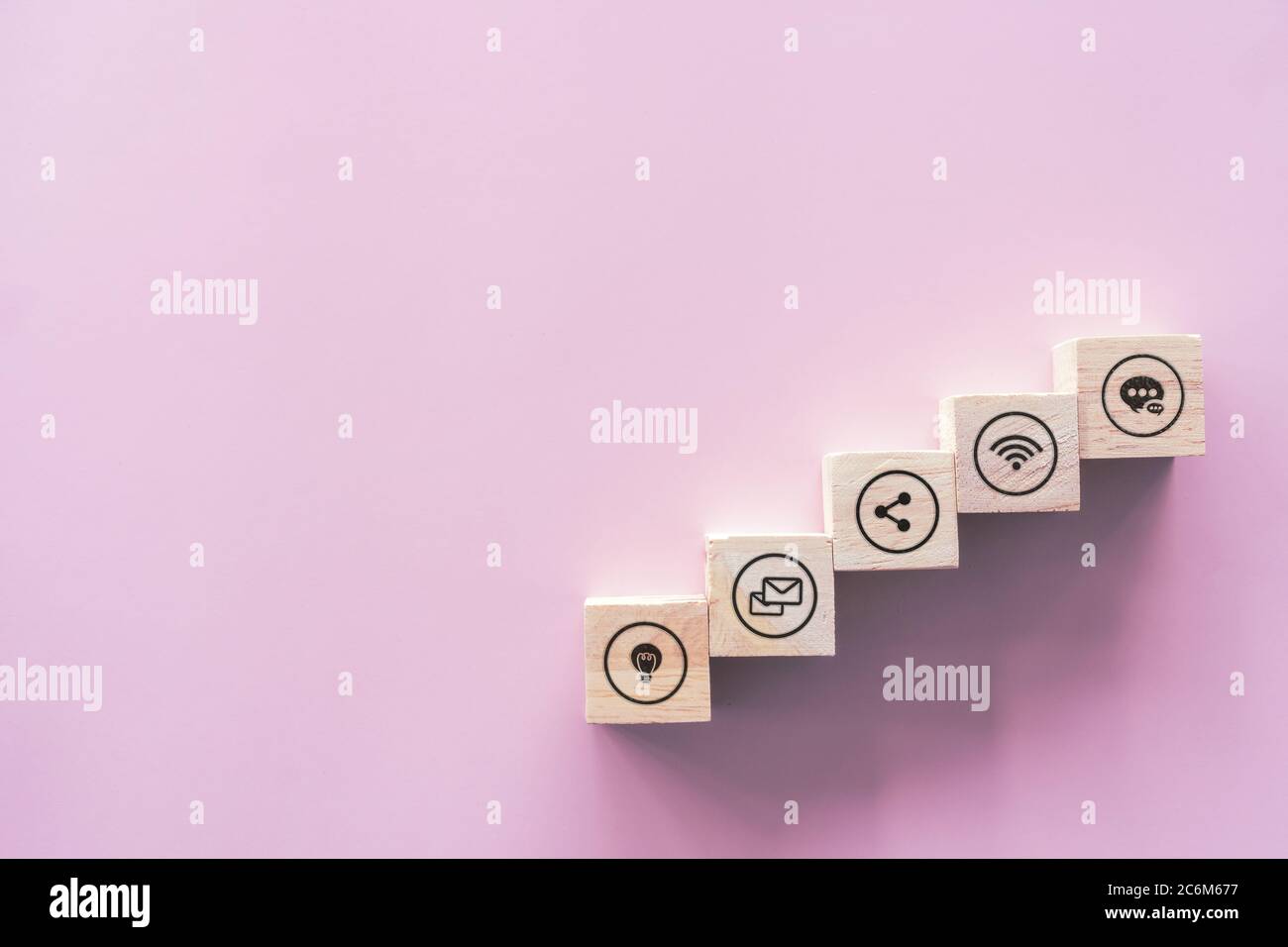 Primo piano di legno blocco impilamento come scala su carta rosa pastello sfondo con spazio di copia. Concetto di icone online aziendali. Foto Stock