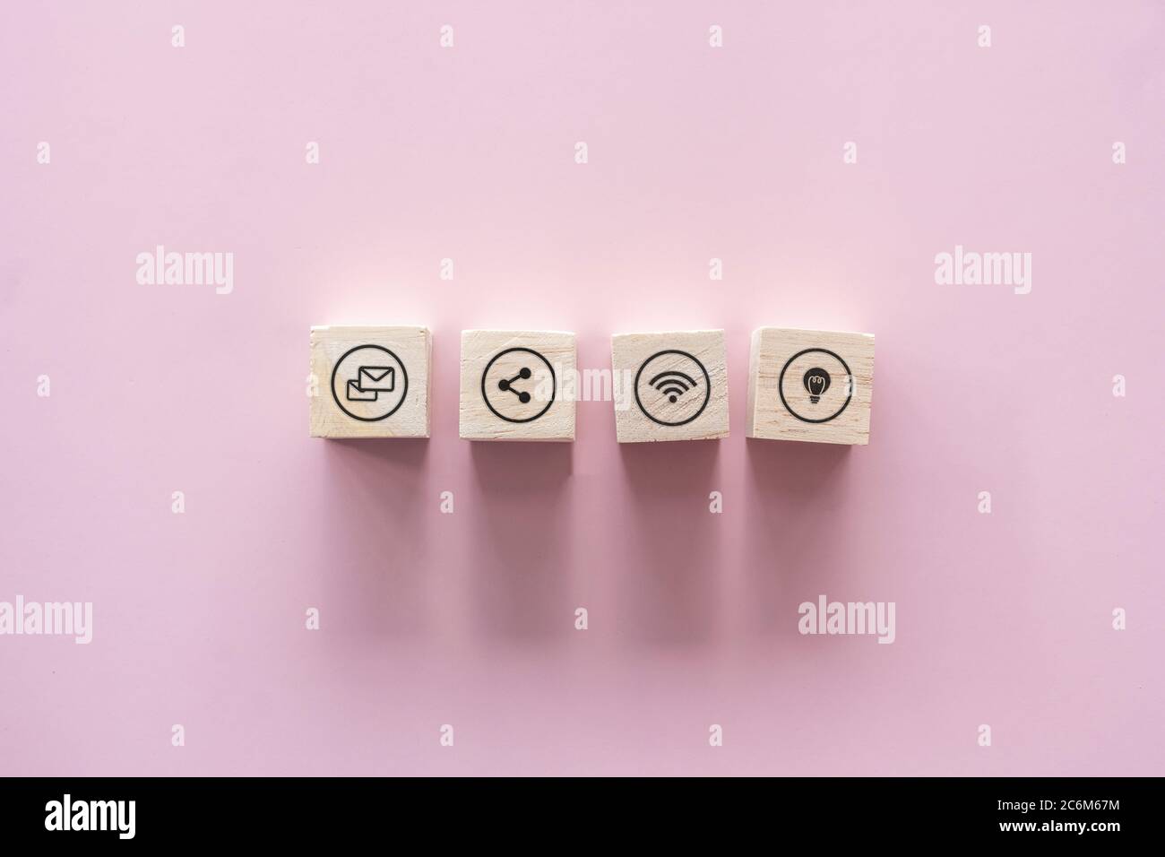 Primo piano di legno blocco impilamento su carta rosa pastello sfondo con spazio di copia. Concetto di icone online aziendali. Foto Stock