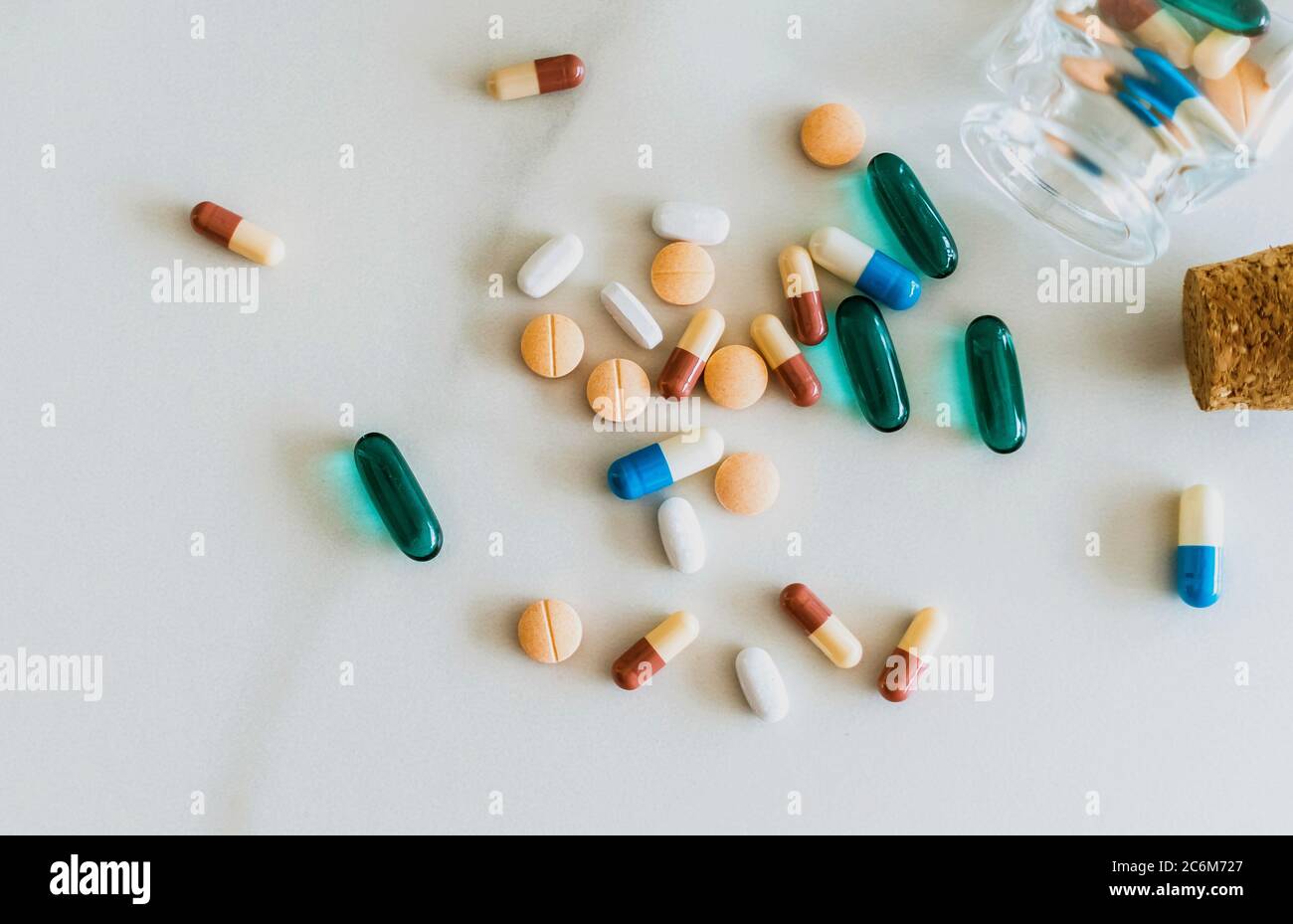 Vista dall'alto delle compresse di medicina versare da pillole flacone di marmo texture sfondo bianco. Concetto di tendenza di stile di vita medico di assistenza sanitaria. Foto Stock