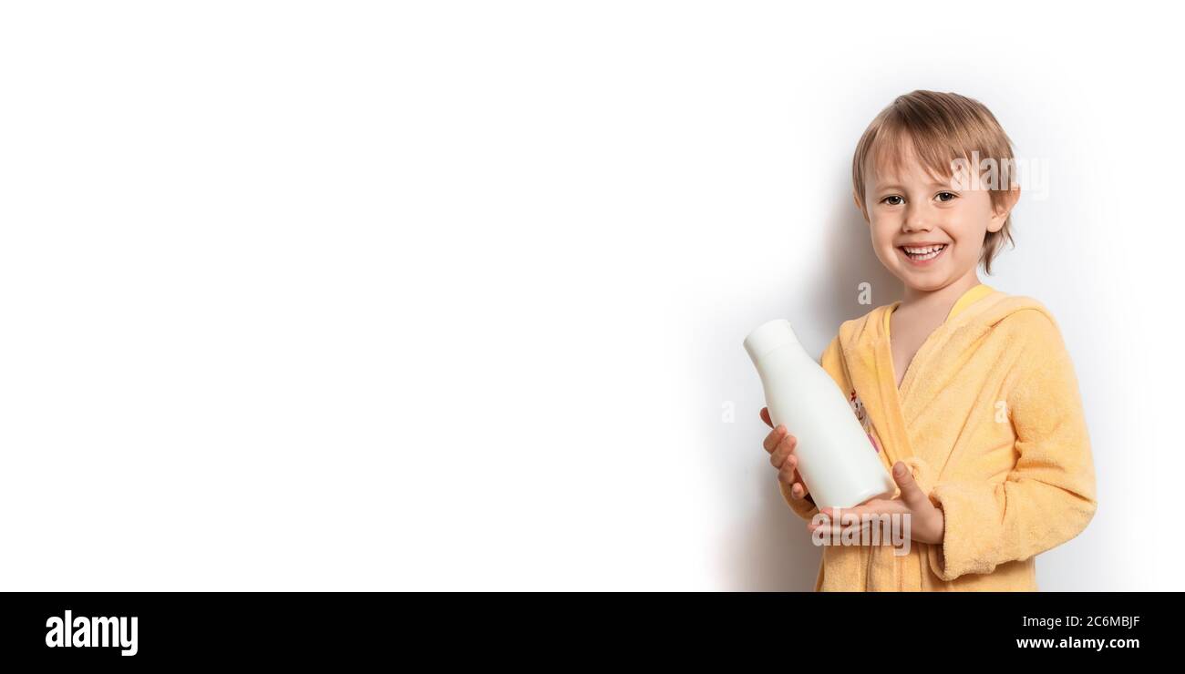 Ragazza carina in un accappatoio giallo con tubo di shampoo bianco in mano Foto Stock