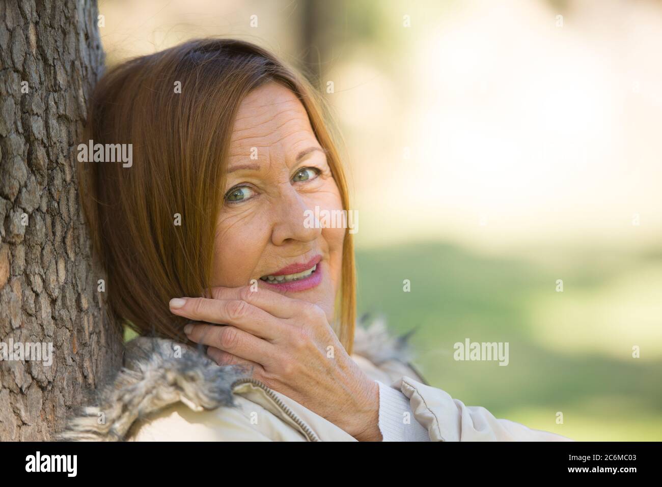 Ritratto attraente bella donna matura seduta felice rilassato, con sorriso amichevole all'aperto, sfondo sfocato. Foto Stock