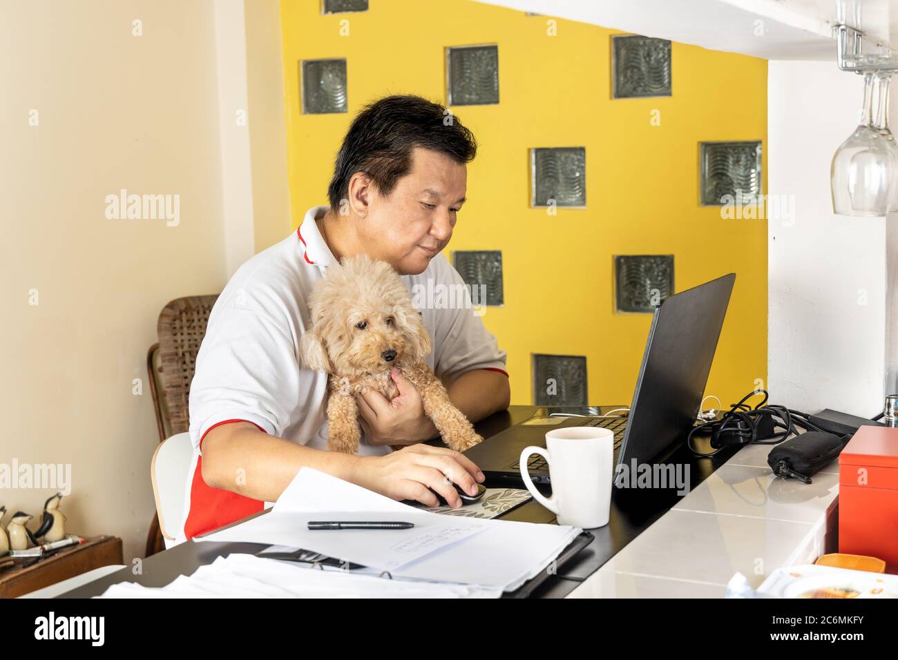 Lavoro maschile asiatico maturato da casa accompagnato da cane durante il blocco in Malesia Foto Stock