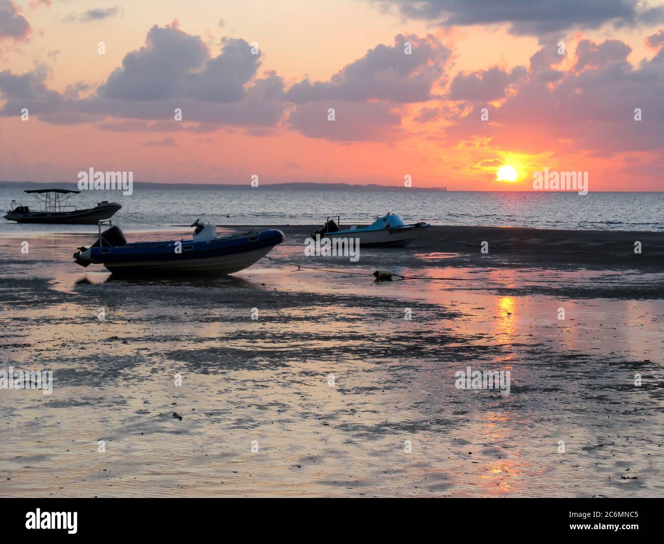 Vari motoscafi fuoribordo sulla spiaggia a bassa marea, a Vilanculos, Mozambico, con l'alba in background Foto Stock
