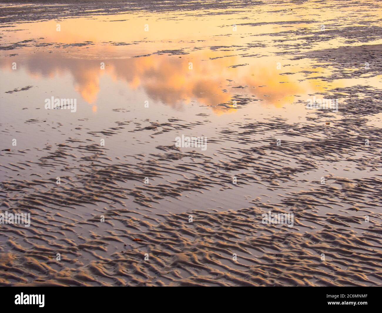 Una piscina marea sulla spiaggia sabbiosa di Vilanculos, Mozambico, che riflette il cielo e le nuvole, mostrando ancora gli ultimi resti dei colori dell'alba Foto Stock
