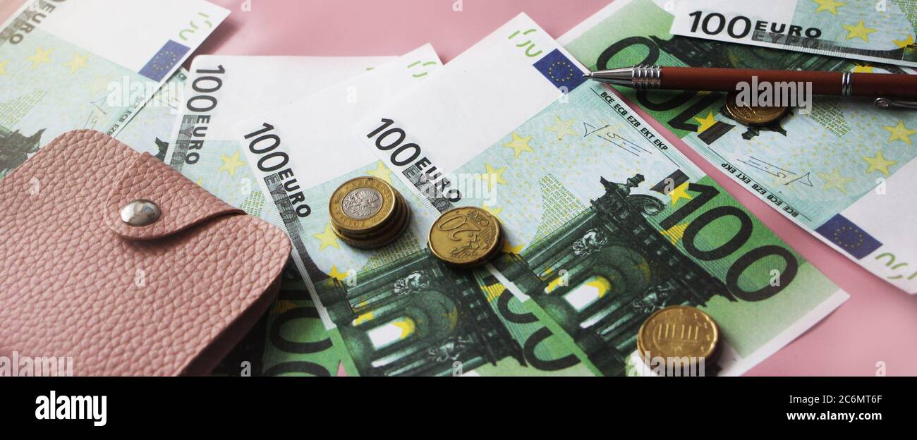 Monete in euro, centinaia di banconote in euro, penna, portafoglio in pelle rosa. Concetto aziendale Foto Stock