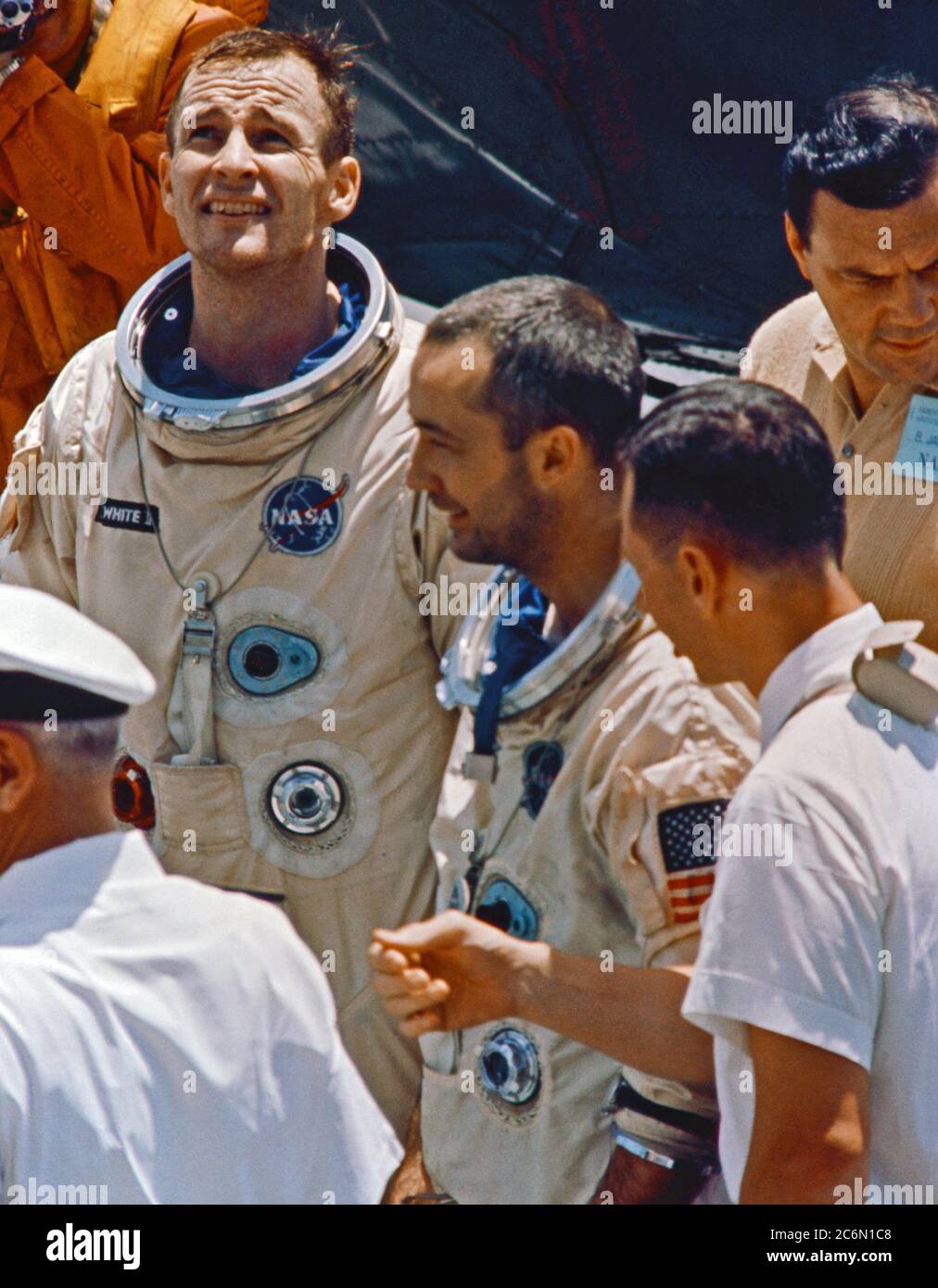 Gli astronauti James McDivitt A. (sinistra), Gemini-Titan 4 comando pilota; e Edward H. White II, pilota, sono visti a parlare con il personale sul recupero nave USS Wasp. Foto Stock