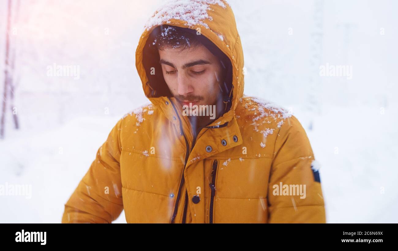 Ritratto di un uomo freddo che indossa un cappotto che ha catturato la nevicata nel freddo nella neve Foto Stock